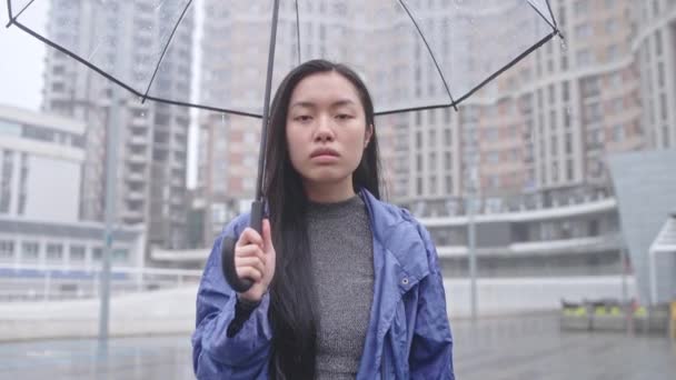Unzufriedene Asiatin Steht Mit Durchsichtigem Regenschirm Auf Der Straße Und — Stockvideo