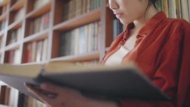 Klasik kitapçıda, şehir kütüphanesinde büyük kitapların sayfalarını karıştıran bir kadın.