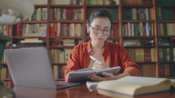 Soustředěný Asijský Student Zapisuje Poznámky Bere Online Lekce Knihovně — Stock video