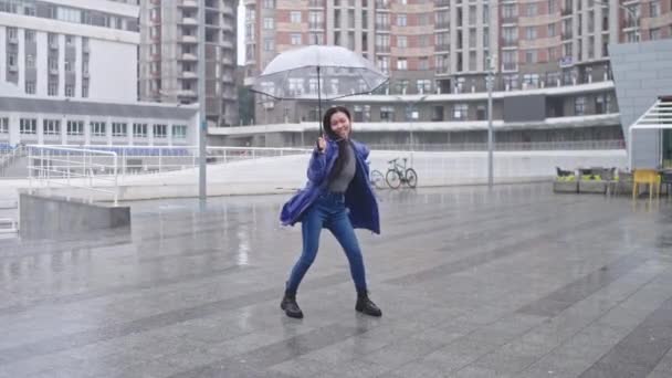 積極的な陽気なアジアの女性が雨の中で踊り 大きな傘の下に隠れて — ストック動画
