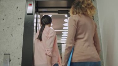 Asansöre binen genç meslektaşlar, iş merkezindeki ofis çalışanları.
