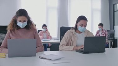 Ofiste çalışan koruyucu maskeli mali analistler, covid-19 önlemleri