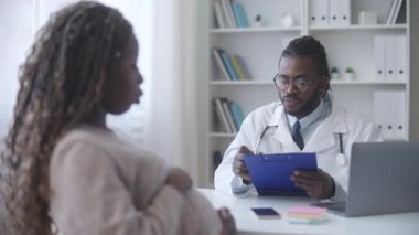 Doğum öncesi kontroller sırasında hastanın semptomlarını yazan özenli bir doğum uzmanı.