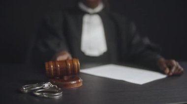 Siyahi yargıç son karar için tokmağı vurdu, kelepçeler masanın üstünde, adalet