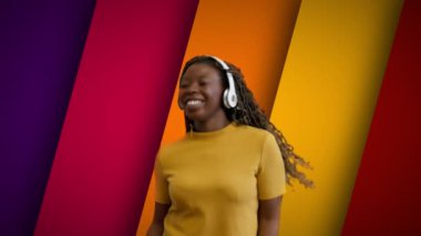 Kulaklıklı güzel bir kadın çok renkli arka planda dans ediyor. Müzik uygulaması.