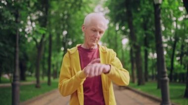 Kıdemli adam egzersizden sonra bilek fitness izleyicisindeki aktivite göstergelerini kontrol ediyor.