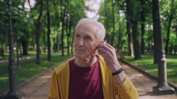 Starší Muž Nasazuje Sluchátka Zapíná Hudbu Jde Běhat Cvičit — Stock video