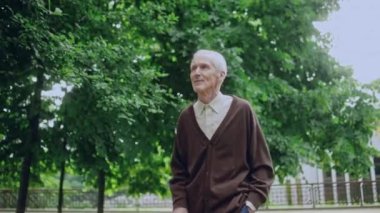 Mutlu olgun bir adam güzel yeşil parkta yürüyor bastonuyla, doğanın tadını çıkarıyor.