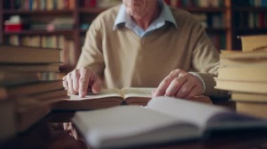 Kıdemli araştırmacı kütüphanede oturmuş, kitap yığınları arasında edebiyat okuyor.
