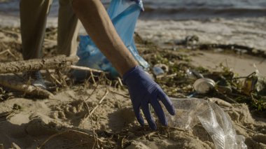 Çevre gönüllüsü plajda plastik atık topluyor, doğayı koruyor