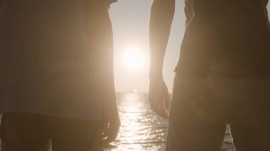 Suyun kenarında yan yana duran, güneşin doğuşunu seyreden, geleceğe bakan iki eşcinsel adam.