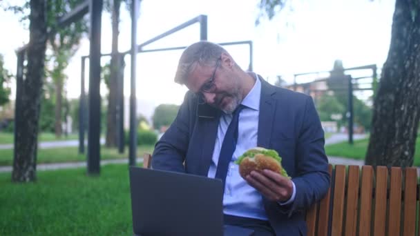 Занятой Бизнесмен Ест Сэндвичи Время Работы Ноутбуке Парке Нездоровая Еда — стоковое видео