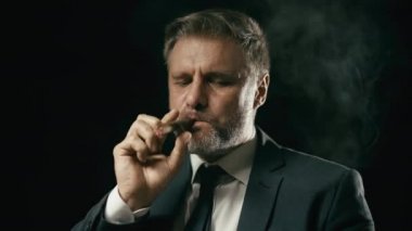 İş adamı puro içiyor, iş stratejisini düşünüyor, ağır çekimde sigara içiyor.