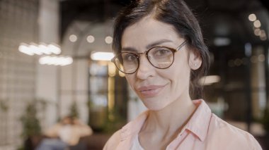 Gözlüklü güzel bir kadın kameraya gülümsüyor, mutlu bir iş kadını, gözleri var.