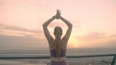 Genç, zinde bir kadın köprüde uzanıyor, muhteşem gündoğumunun tadını çıkarıyor.