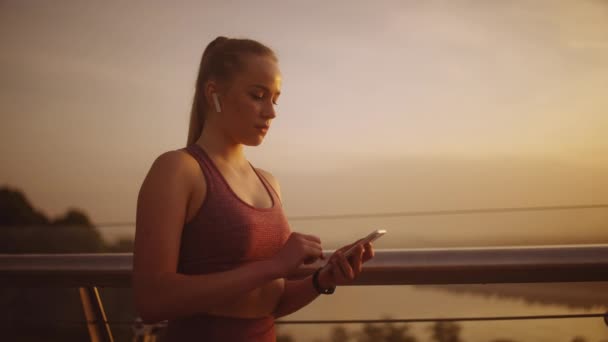 スマートフォンで音楽をオンにし 実行のために行く自信のスポーツ女性 — ストック動画