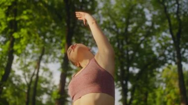 Güzel atletik kadın sırt kaslarını esnetiyor, dışarıda spor yapıyor, ısınıyor.