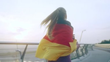 Omuzlarında Almanya bayrağı taşıyan vatansever sarışın kadın.