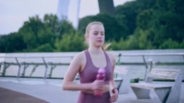 Dişi koşucu su içmek ve nefes almak için ara veriyor, koşmaya devam ediyor.