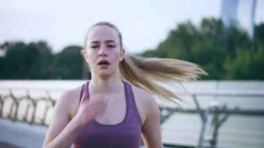 Uykulu kadın köprüde koşuyor ve esniyor, yorucu bir sabah antrenmanı yapıyor.