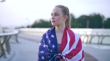 Mutlu genç kadın, omuzlarında Amerikan bayrağı, hakları ve özgürlükleriyle gururla ayakta duruyor.
