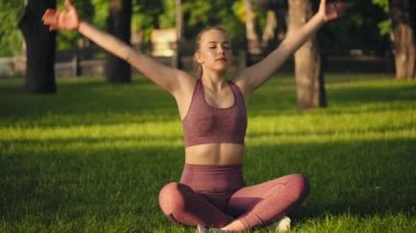 Çekici genç kadın meditasyon sırasında sakince nefes alıyor, lotus pozunda oturuyor.