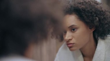 Sabahları aynaya bakan mutsuz bir kadın, solgun bir cilt, vitamin eksikliği.