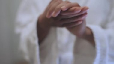 Bornozlu genç bir kadın el kremi sürüyor, gece rutini, cilt bakımı.