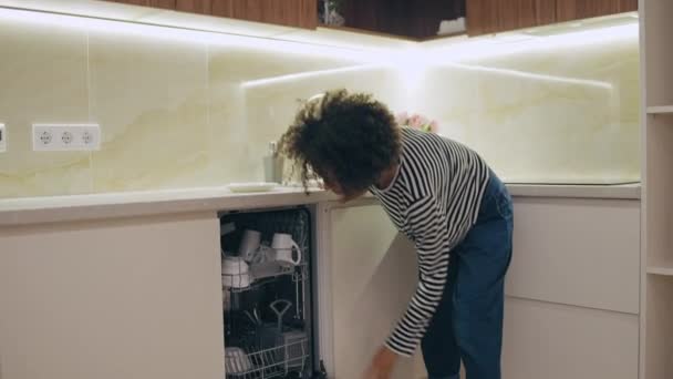 卷发女人把盘子放在洗碗机里 日常打扫房间 — 图库视频影像