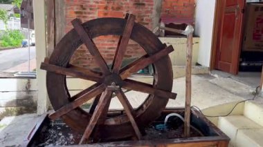 Geleneksel ahşap su çarkı kırsal alanda yavaşça dönüyor, sulama ve çiftçilik için suyu kaldırmak için akan akarsu kullanıyor, sürdürülebilir yaşamın sembolü.