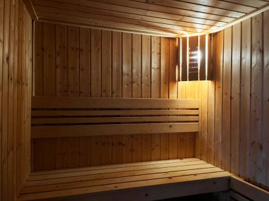 Ilık, ahşap bir sauna iç mekanı yumuşak ortam ışığı ve temiz yatay bank hatları, sakinlik, rahatlama ve spa temalı video içeriği için ideal sakin ve yatıştırıcı bir atmosfer yaratıyor.