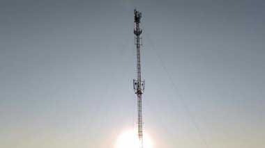 Telekomünikasyon kulesi, günbatımında bir telekomünikasyon kulesinin havadan görünüşü arka planda kırsal manzara, kablosuz iletişimi ve kırsal altyapıyı sembolize ediyor.