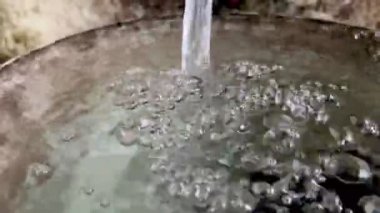 Taze temiz su bir kabın içine düşer güzel kabarcıklar yaratır ve doğal ışıklandırmayla yakın çekim görüntüsüne sıçrar.