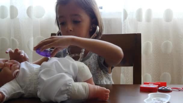 Девушка, играющая в доктора с куклой — стоковое видео