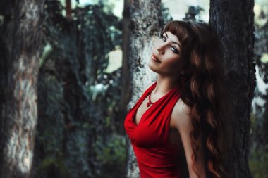 Ormanın içinde Kırmızı elbiseli uzun dalgalı saçlı kız