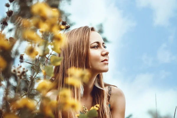 Schönes, natürliches Mädchen zwischen gelben Blumen und Wolken im Profil. — Stockfoto
