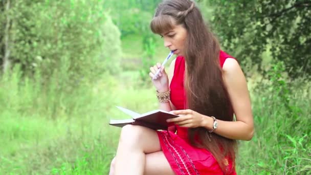 Una chica escribe en un cuaderno sobre la naturaleza — Vídeo de stock