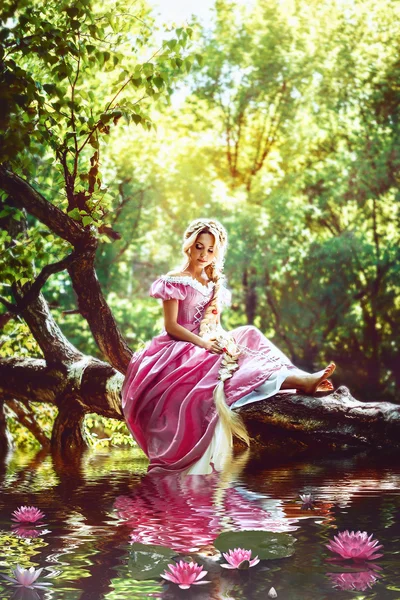 Schöne Mädchen mit langen Haaren zu einem Zopf geflochten, in Korsett und herrlichem rosa Kleid an den Seerosen. — Stockfoto