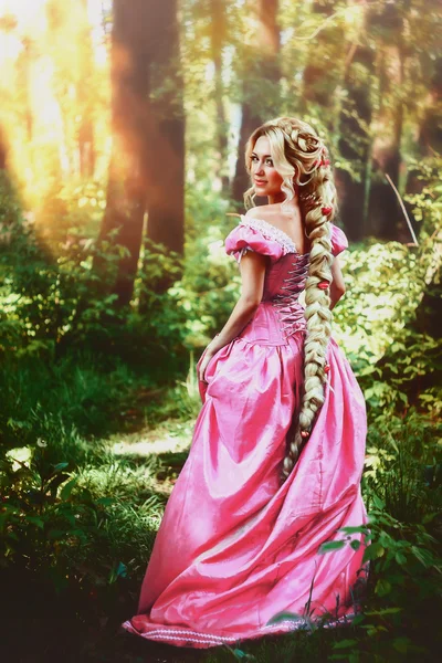 Beautiful girl with long hair braided in a braid, in corset and magnificent pink dress. — Stock Photo, Image