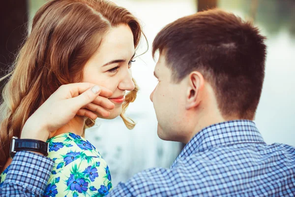 Pair of lovers near the lake touches to each other and smiling. — Stock Photo, Image