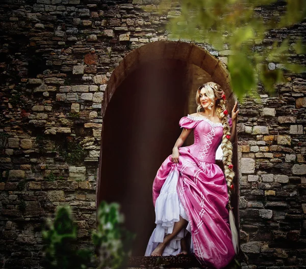 Beautiful girl with long hair braided in a braid, in corset and magnificent pink dress. — Stock Photo, Image