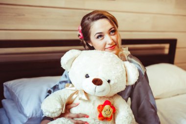 Yatak yumuşak oyuncak ile oturan kız