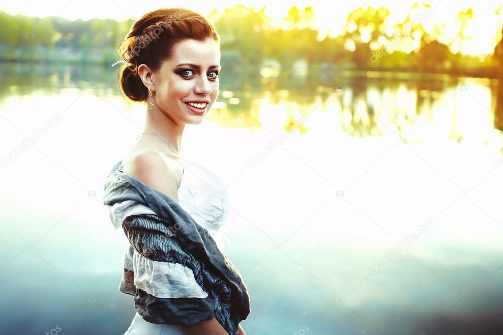 girl stands by a river at sunset