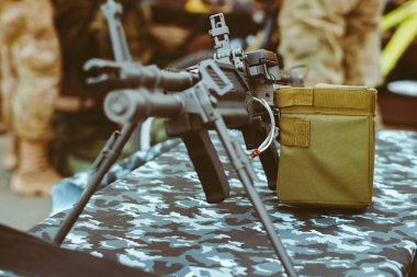 Tezgahta otomatik tüfekli bir adam var. Silahlar.