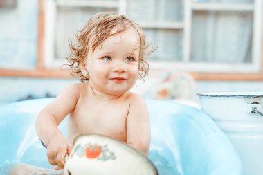 Küçük bir çocuk bir köy evinin yakınındaki sokakta banyo yapıyor.