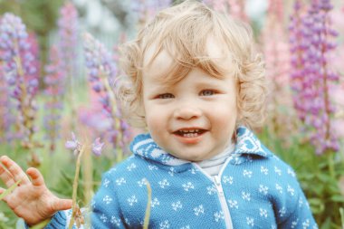 Mutlu çocuk bir yaz günü çimlerin arasında oynuyor.