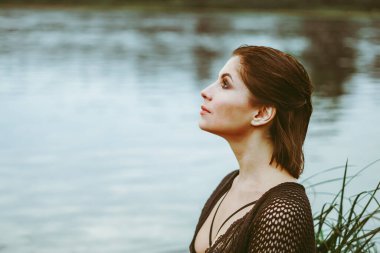 Nehir kenarındaki çimlerin arasında güzel bir elbise içinde güzel bir kız.