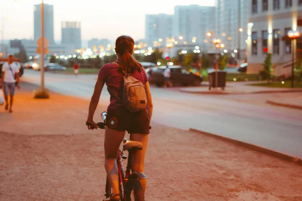 夜の街の灯りの中自転車に乗る女の子が — ストック写真