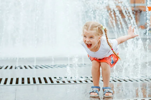 little girl near the fountain in a red skirt with pigtails