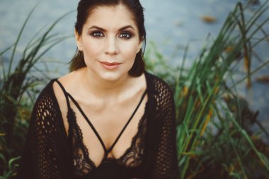 Nehir kenarındaki çimlerin arasında güzel bir elbise içinde güzel bir kız.